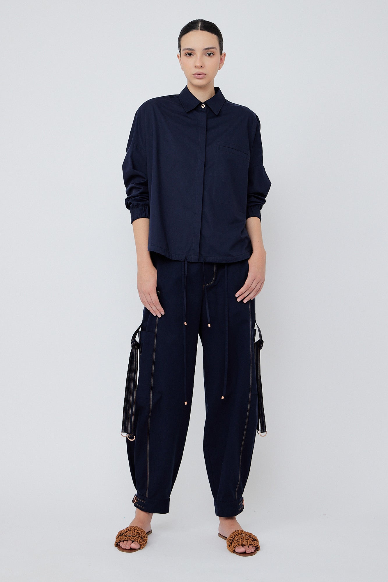 Paloma wide-leg pants made from 100% Pima cotton, featuring front and back patch pockets, side pockets with buckles, adjustable drawstring waistband, and double button cuffs.