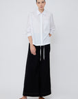 The Hebe Blouse in crisp white, featuring its clean lapel collar and innovative asymmetrical design.