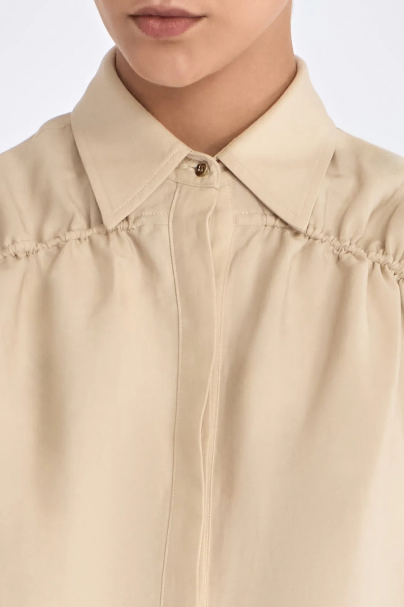 Close-up of the signature metal button and the natural texture of the linen blend on the Ecru Ailani Jacket.