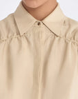 Close-up of the signature metal button and the natural texture of the linen blend on the Ecru Ailani Jacket.