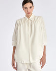 The Ailani Jacket in Off White, highlighting its clean architectural lines and drawstring detail.