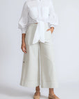 Person wearing a white shirt and light-colored pants on a plain background