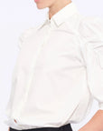 Detail shot of the sculptural puff sleeve and the premium cotton fabric of the white Bimba Blouse.