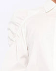 Detail shot of the sculptural puff sleeve and the premium cotton fabric of the white Bimba Blouse.
