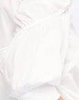 Detail shot of the sculptural puff sleeve and the premium cotton fabric of the white Bimba Blouse.