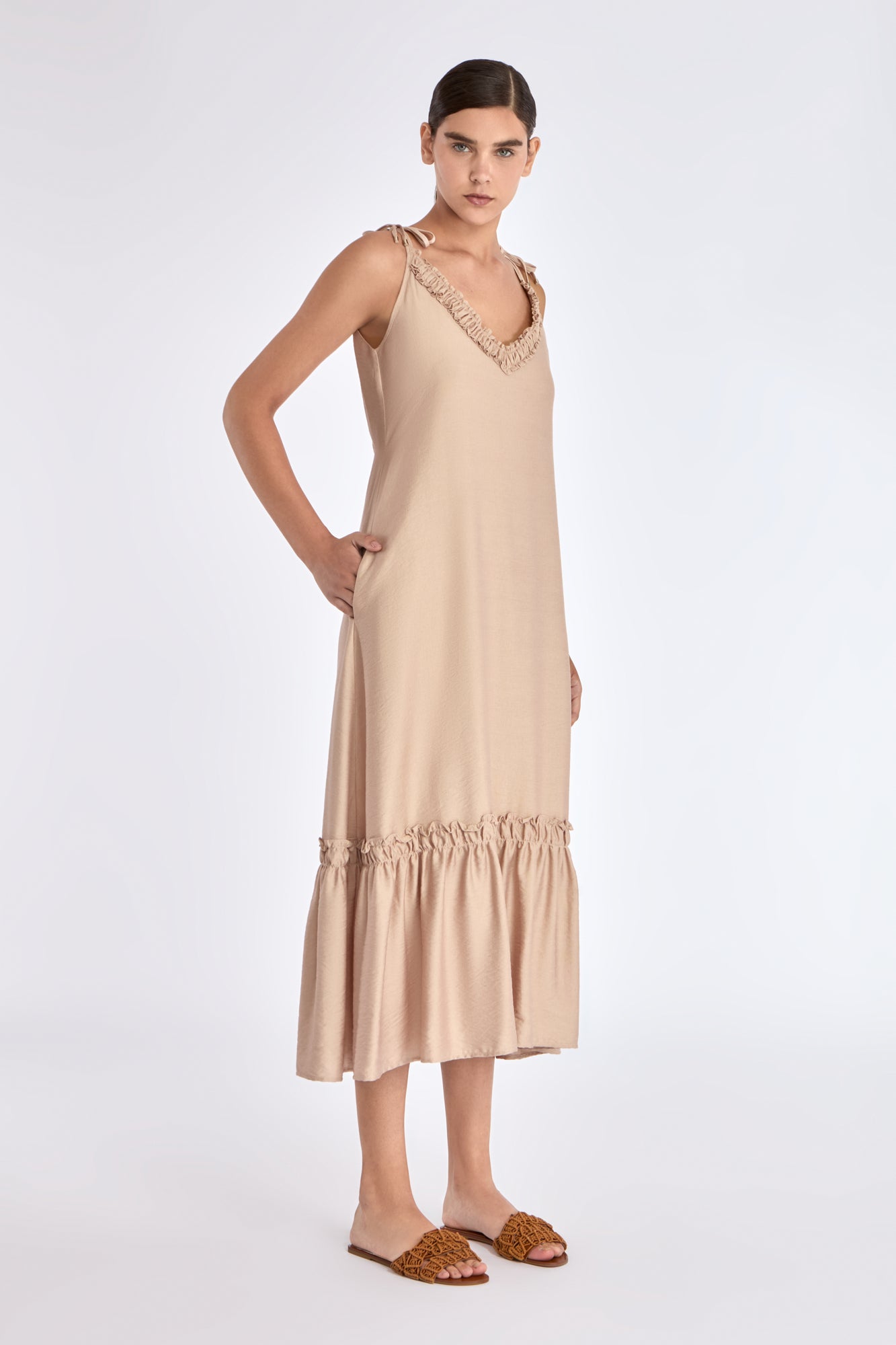 Side view of the Nude Blake Dress, showcasing the elegant movement of its gathered and pleated skirt.