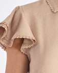 Detail shot of the delicate ruffle and tonal trim on the sleeve of the Nude Clark Blouse.