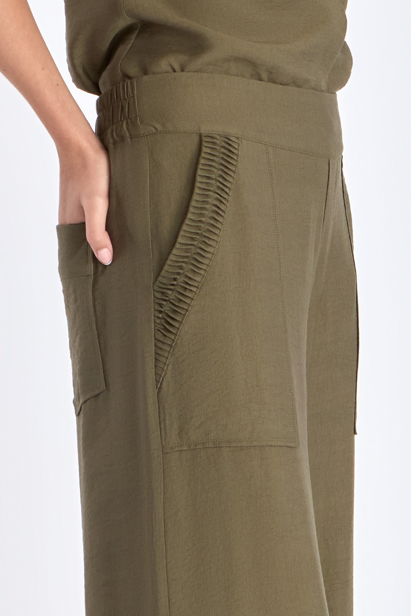 Detail of the tone-on-tone trim on the hem of the olive Clark Ease Pant, a soft knit trouser.