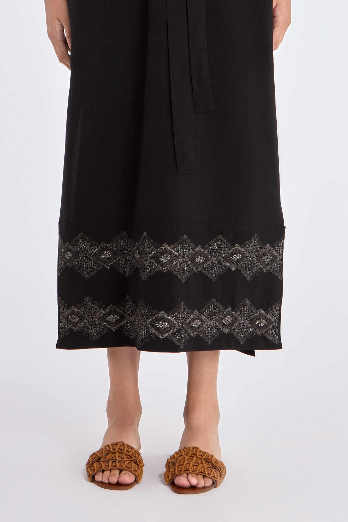Close-up of the handcrafted AMEDBAM embroidery on the hem of the black Denver Dress.