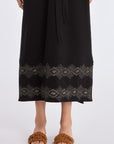 Close-up of the handcrafted AMEDBAM embroidery on the hem of the black Denver Dress.