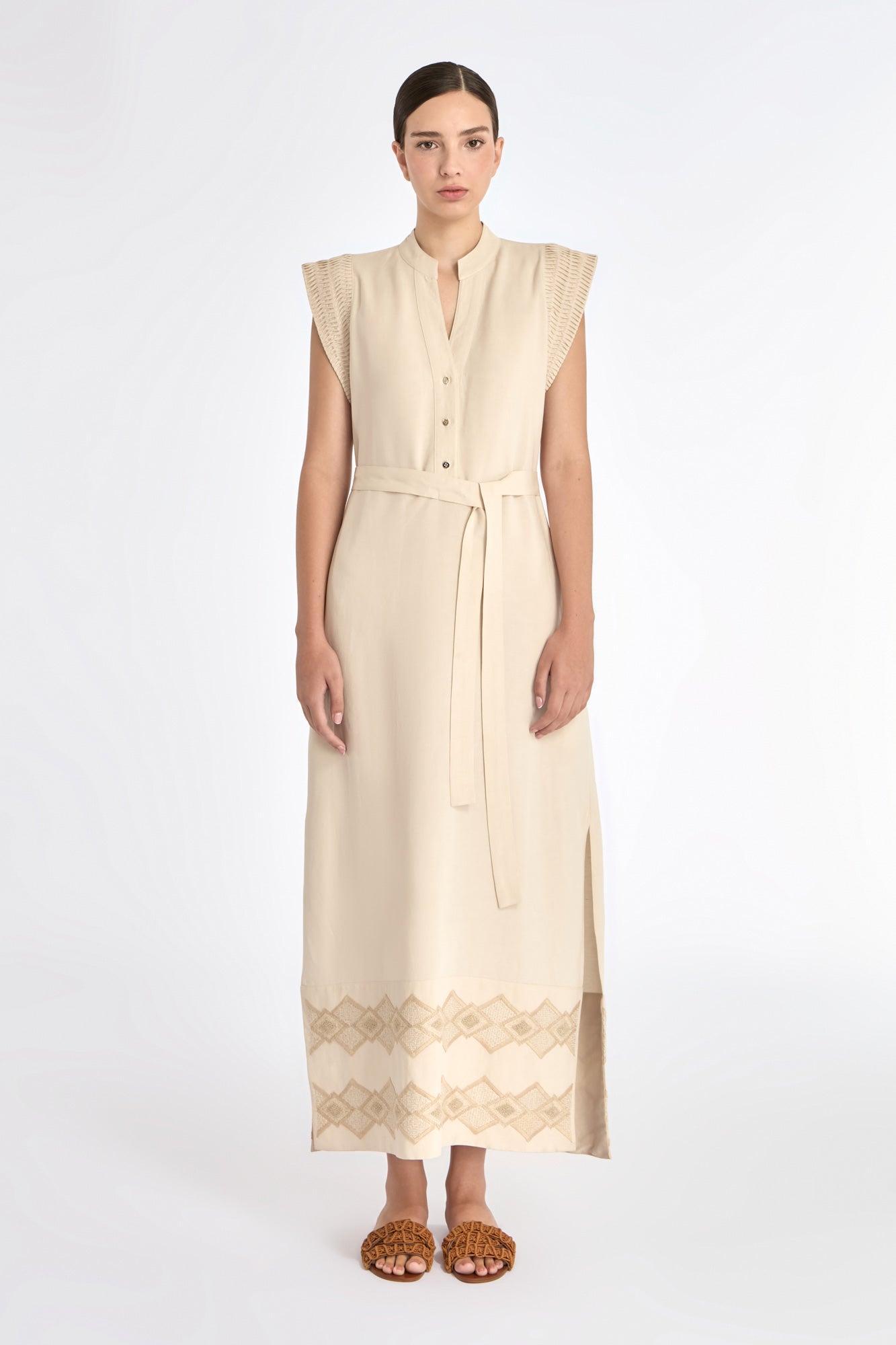 Denver Dress in Ecru – Sleeveless linen midi dress with embroidered hem by AMEDBAM, metal buttons, and fabric belt.