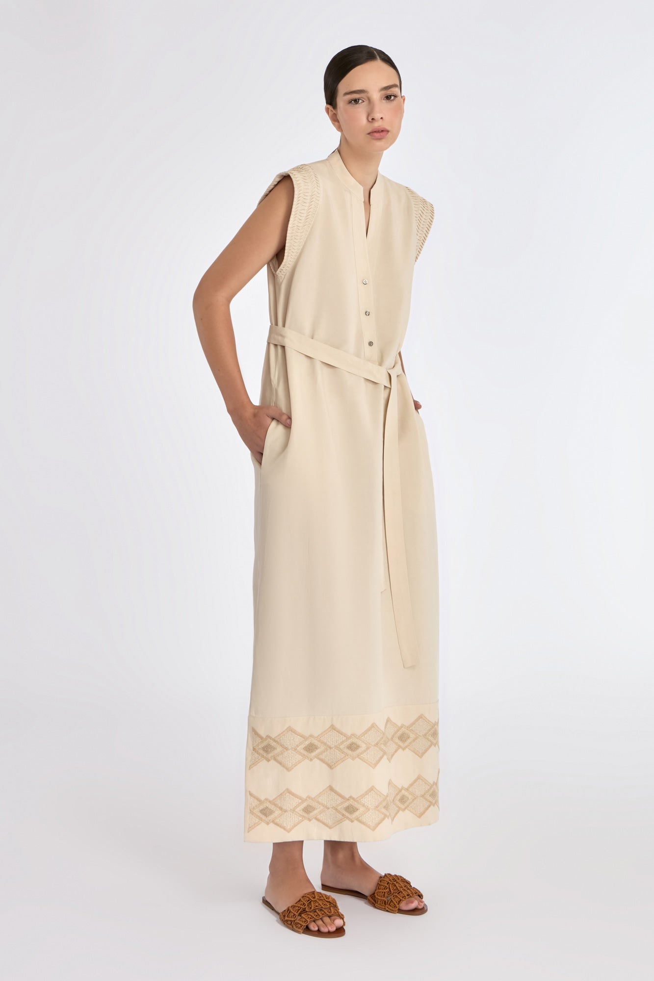 Denver Dress in Ecru – Sleeveless linen midi dress with embroidered hem by AMEDBAM, metal buttons, and fabric belt.
