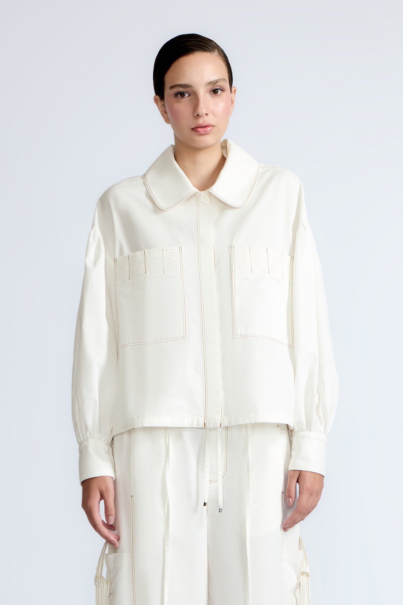 Gwen Jacket in Off White – Cropped cotton jacket with front pleats, shirt collar, and patch pockets.
