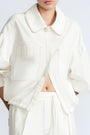 Gwen Jacket in Off White – Cropped cotton jacket with front pleats, shirt collar, and patch pockets.