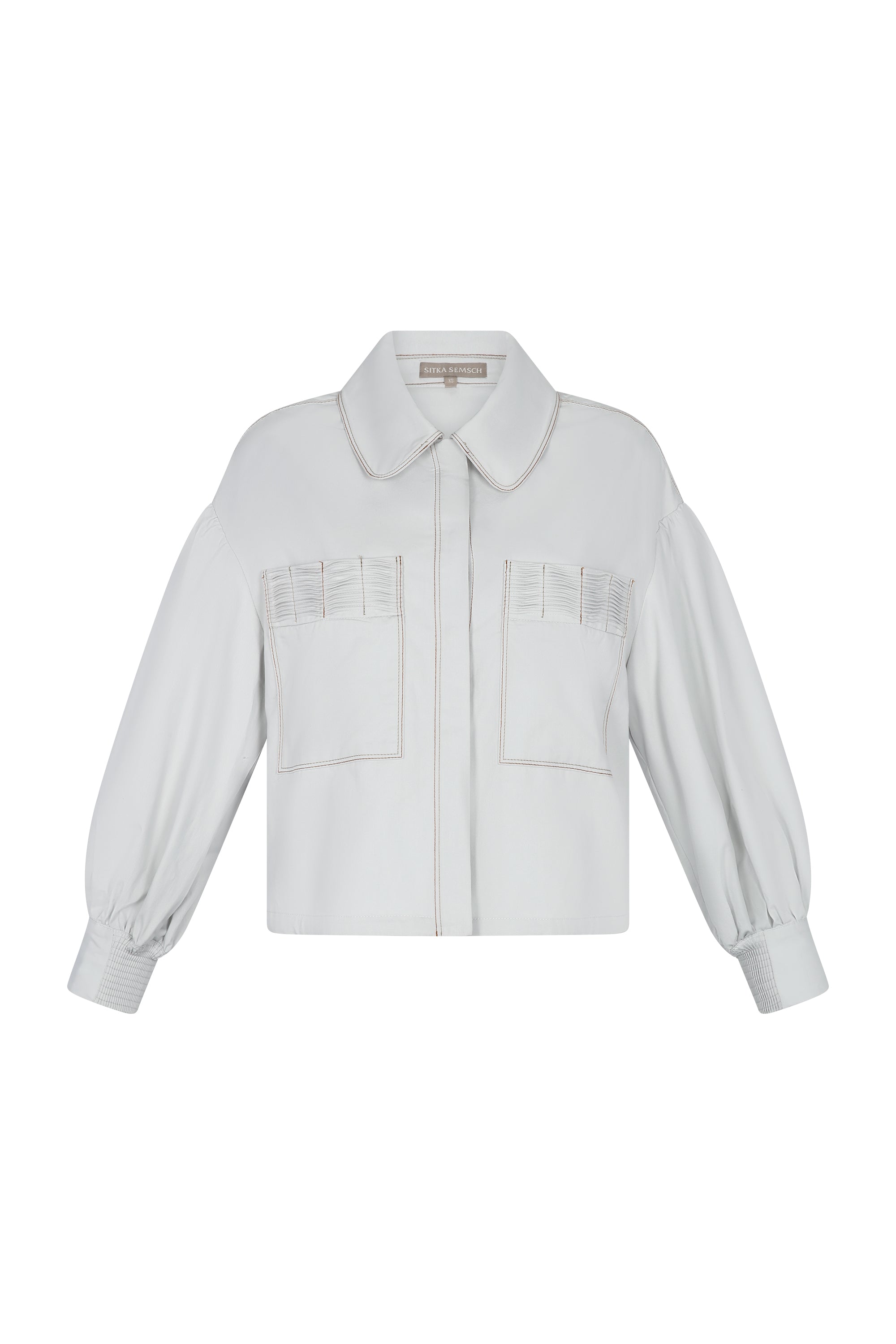 Gwen Jacket in Silver – Cropped cotton jacket with structured pleats, patch pockets, and a modern cut.