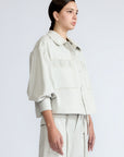 Gwen Jacket in Silver – Cropped cotton jacket with structured pleats, patch pockets, and a modern cut.