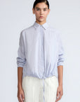 Hebe Blouse in Light Blue Stripes – Relaxed blouse with lapel collar, hidden buttons, asymmetrical hem, and elasticized long sleeves.
