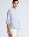 Hebe Blouse in Light Blue Stripes – Relaxed blouse with lapel collar, hidden buttons, asymmetrical hem, and elasticized long sleeves.