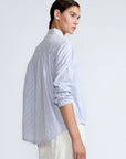 Hebe Blouse in Light Blue Stripes – Relaxed blouse with lapel collar, hidden buttons, asymmetrical hem, and elasticized long sleeves.