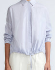 Hebe Blouse in Light Blue Stripes – Relaxed blouse with lapel collar, hidden buttons, asymmetrical hem, and elasticized long sleeves.