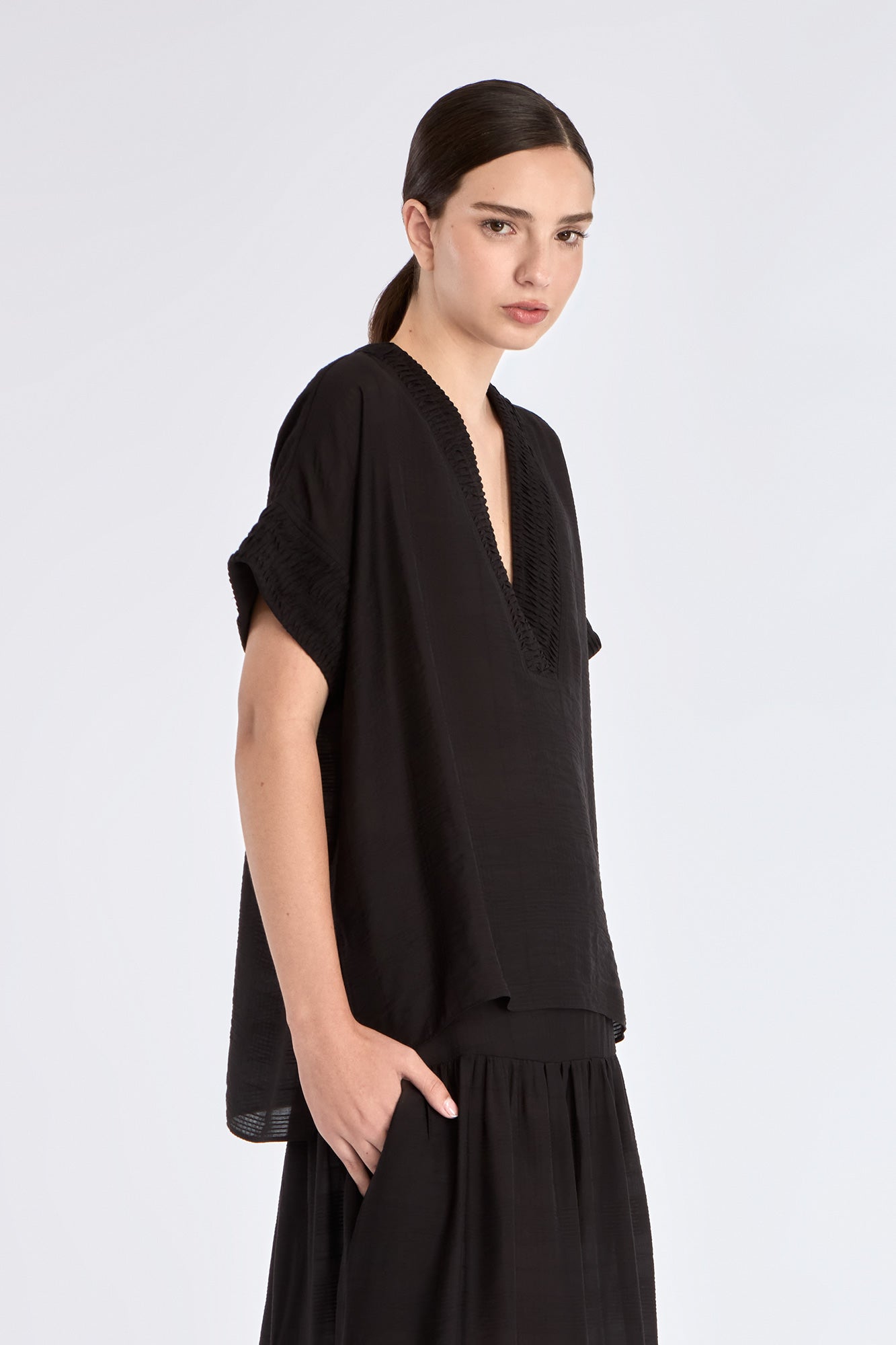 Side profile of the black Ivy Blouse, highlighting the fluid drape of the woven fabric.