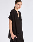 Side profile of the black Ivy Blouse, highlighting the fluid drape of the woven fabric.