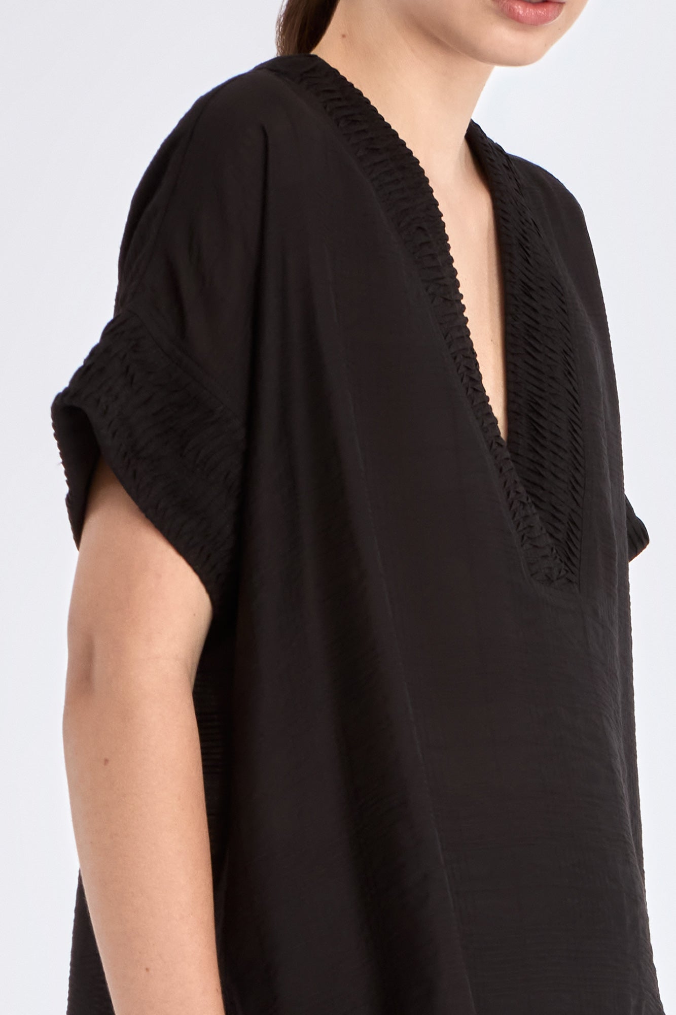 Close-up of the delicate tonal trim detailing on the V-neckline of the black Ivy Blouse.
