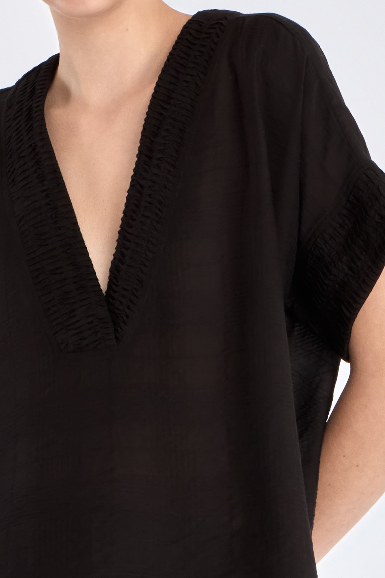 Close-up of the delicate tonal trim detailing on the V-neckline of the black Ivy Blouse.