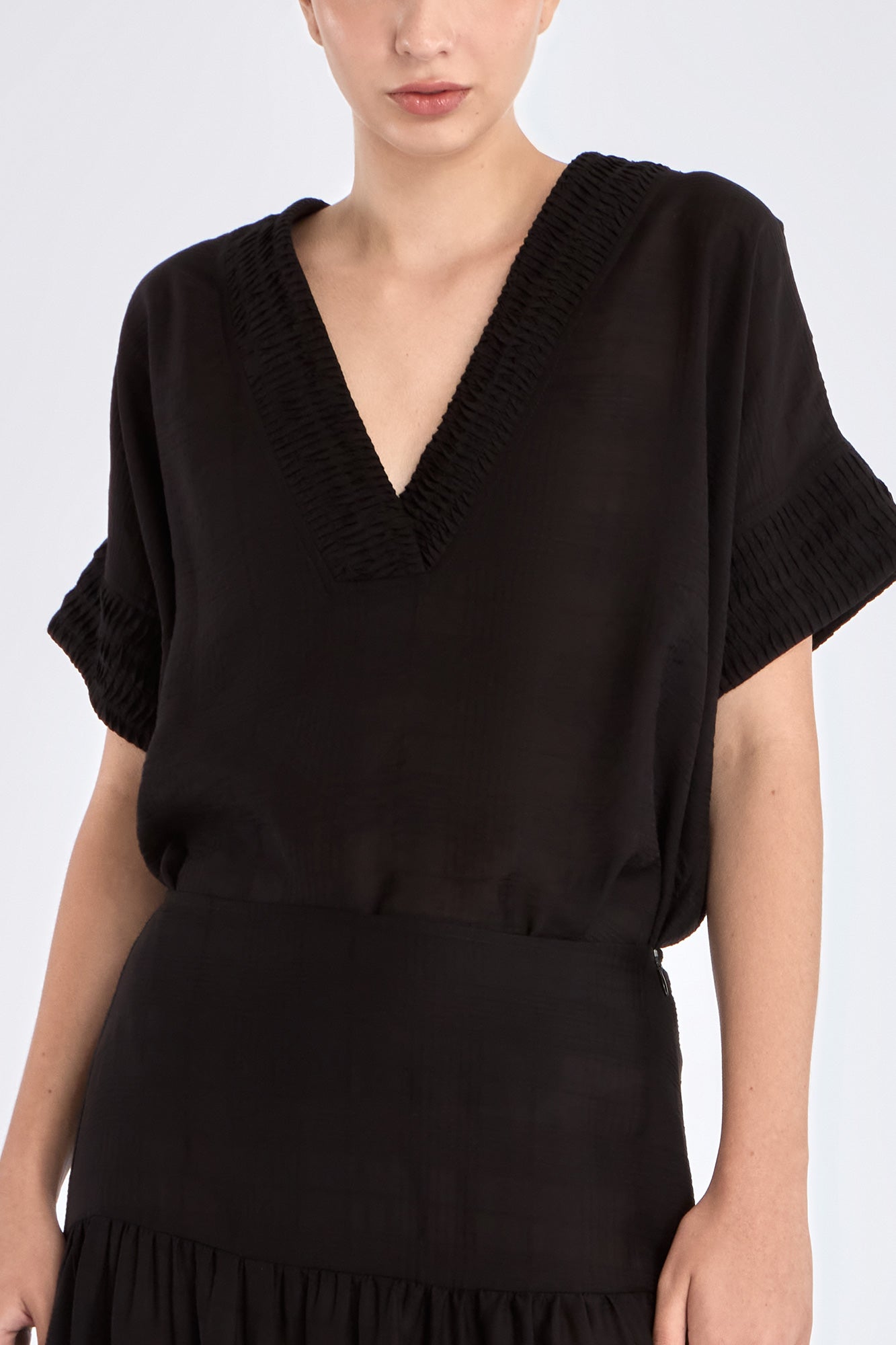 Close-up of the delicate tonal trim detailing on the V-neckline of the black Ivy Blouse.