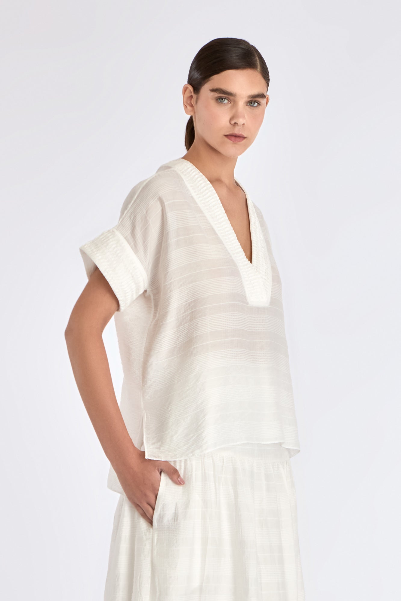 Side view of the Off White Ivy Blouse, showcasing the soft drape of its short sleeves.