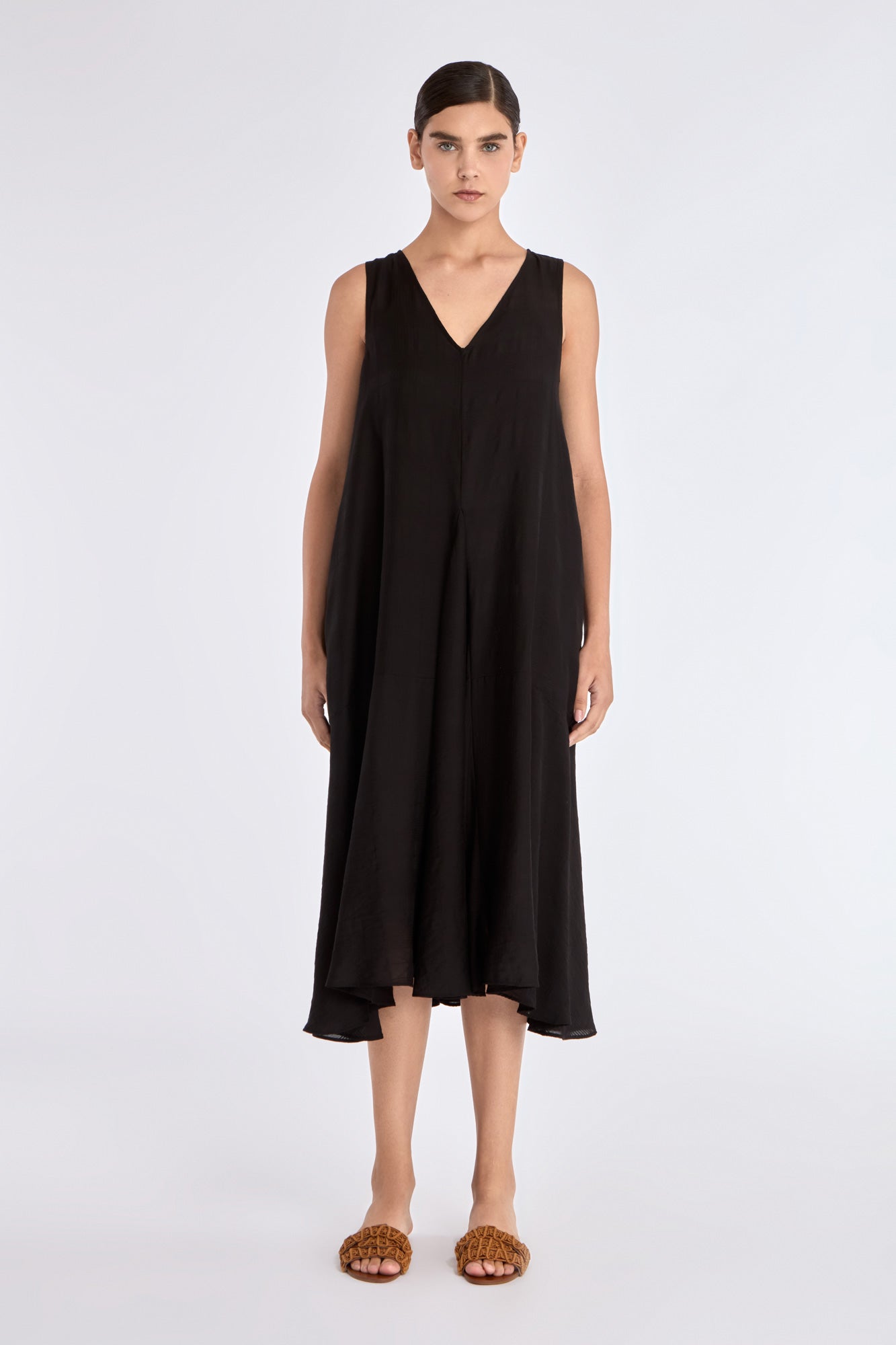 The Lenox Dress in black, styled to showcase its elegant V-neck and voluminous godet skirt.