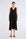The Lenox Dress in black, styled to showcase its elegant V-neck and voluminous godet skirt.