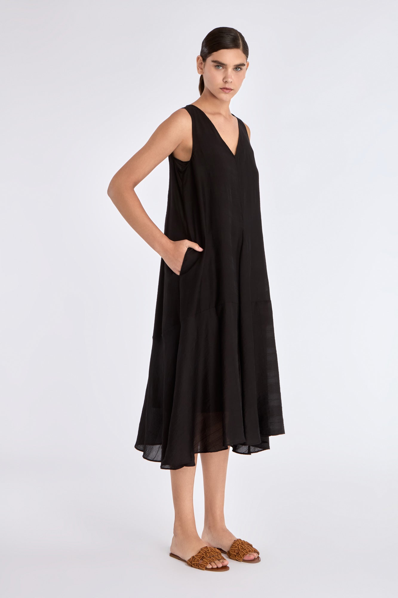 Side silhouette of the black Lenox Dress, emphasizing the dynamic flare created by the godet panels.
