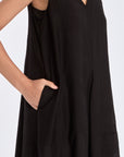 The Lenox Dress in black, styled to showcase its elegant V-neck and voluminous godet skirt.