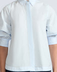 Lina Blouse in Light Blue – Cotton shirt with shirt collar, hidden button closure, ¾ balloon sleeves, and elastic cuffs.