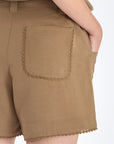 Lira Short in Taupe – Chic mid-rise linen shorts with elasticated waistband, metal-tipped belt, and patch pocket detailing.