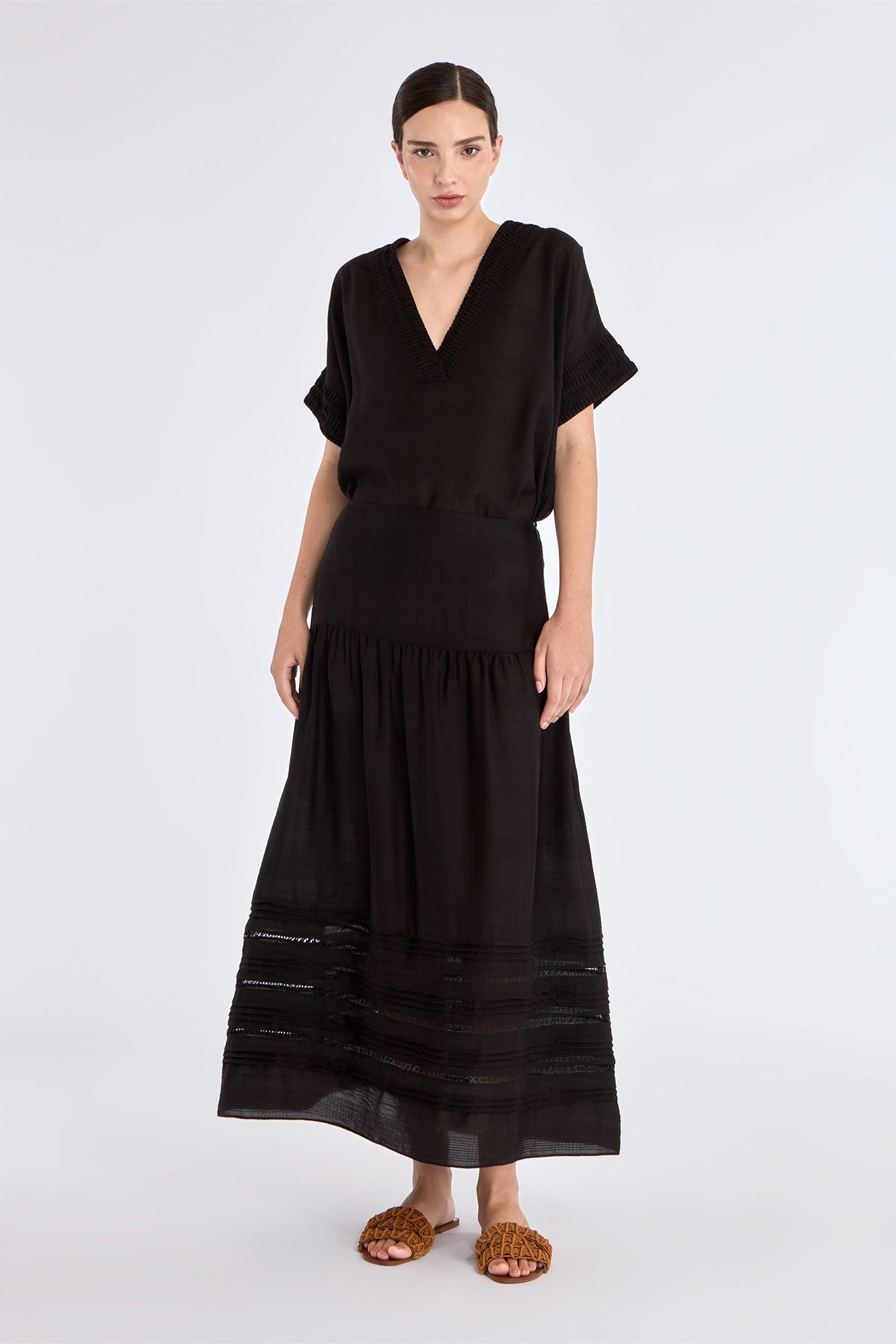 The Luanda Skirt in black, styled to showcase its high-waist fit and voluminous midi silhouette.