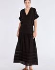 The Luanda Skirt in black, styled to showcase its high-waist fit and voluminous midi silhouette.