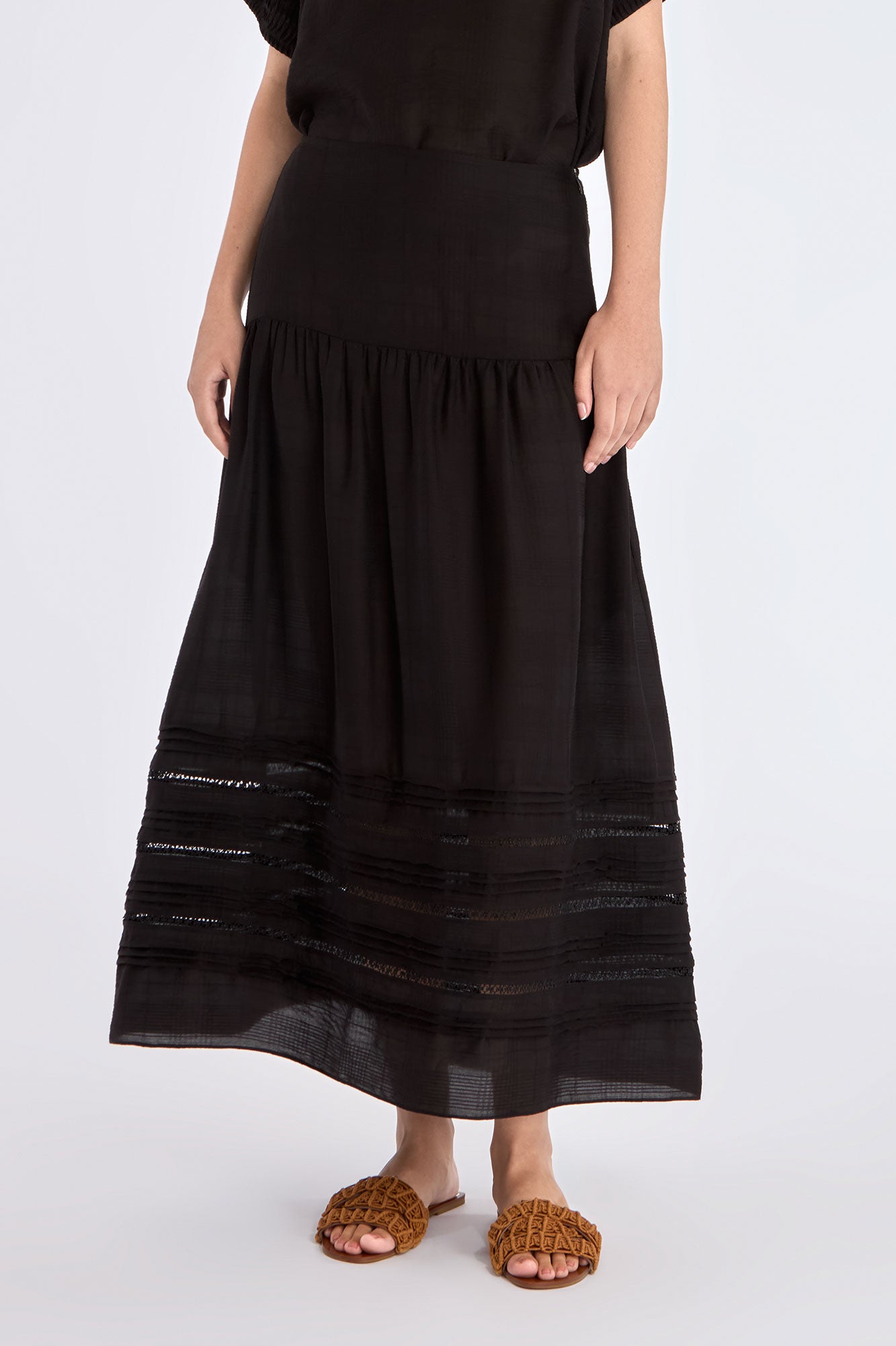 The Luanda Skirt in black, styled to showcase its high-waist fit and voluminous midi silhouette.