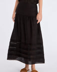 The Luanda Skirt in black, styled to showcase its high-waist fit and voluminous midi silhouette.