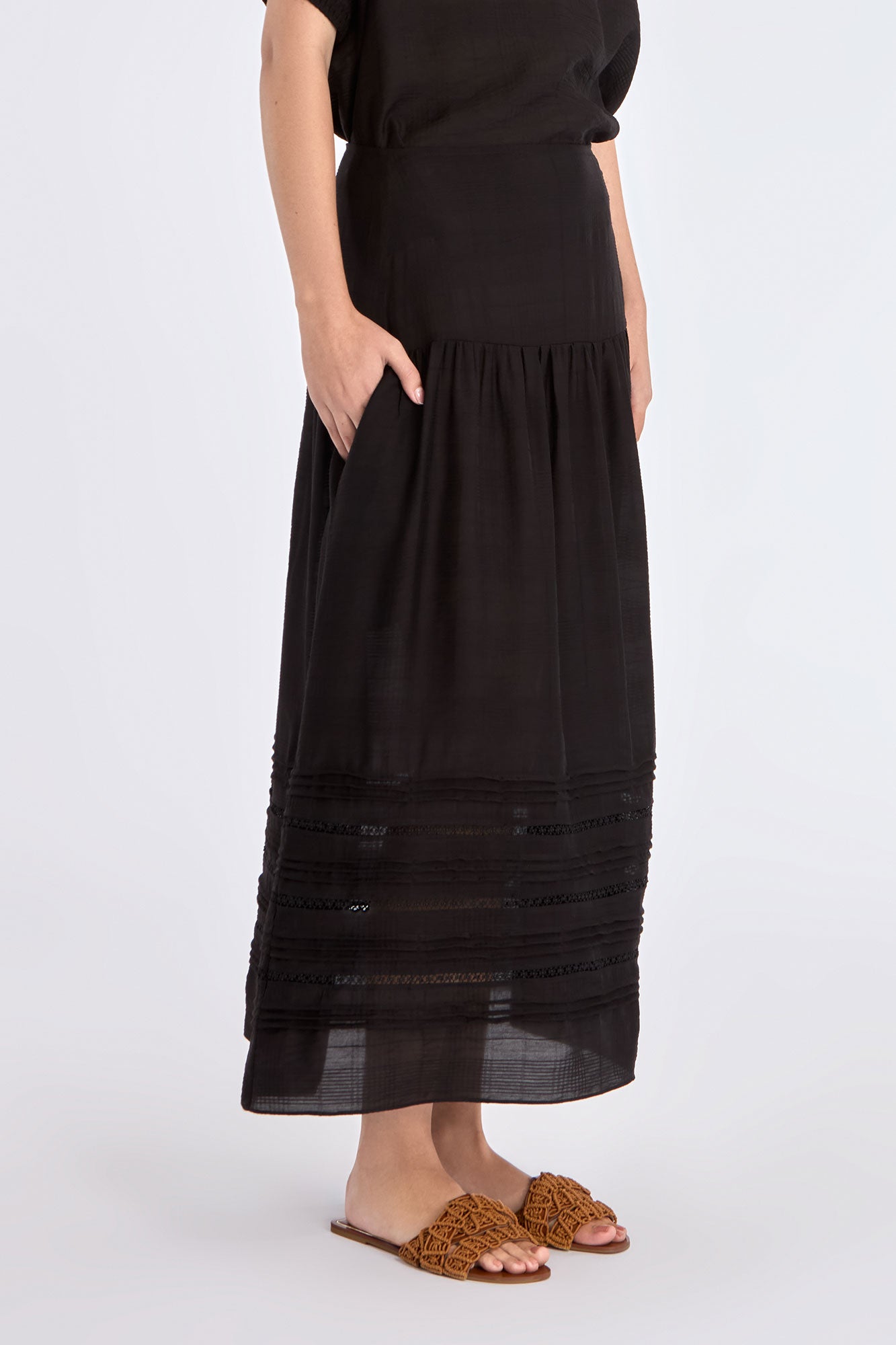 Side view of the black Luanda Skirt, emphasizing the elegant movement of its gathered design.