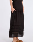 Side view of the black Luanda Skirt, emphasizing the elegant movement of its gathered design.