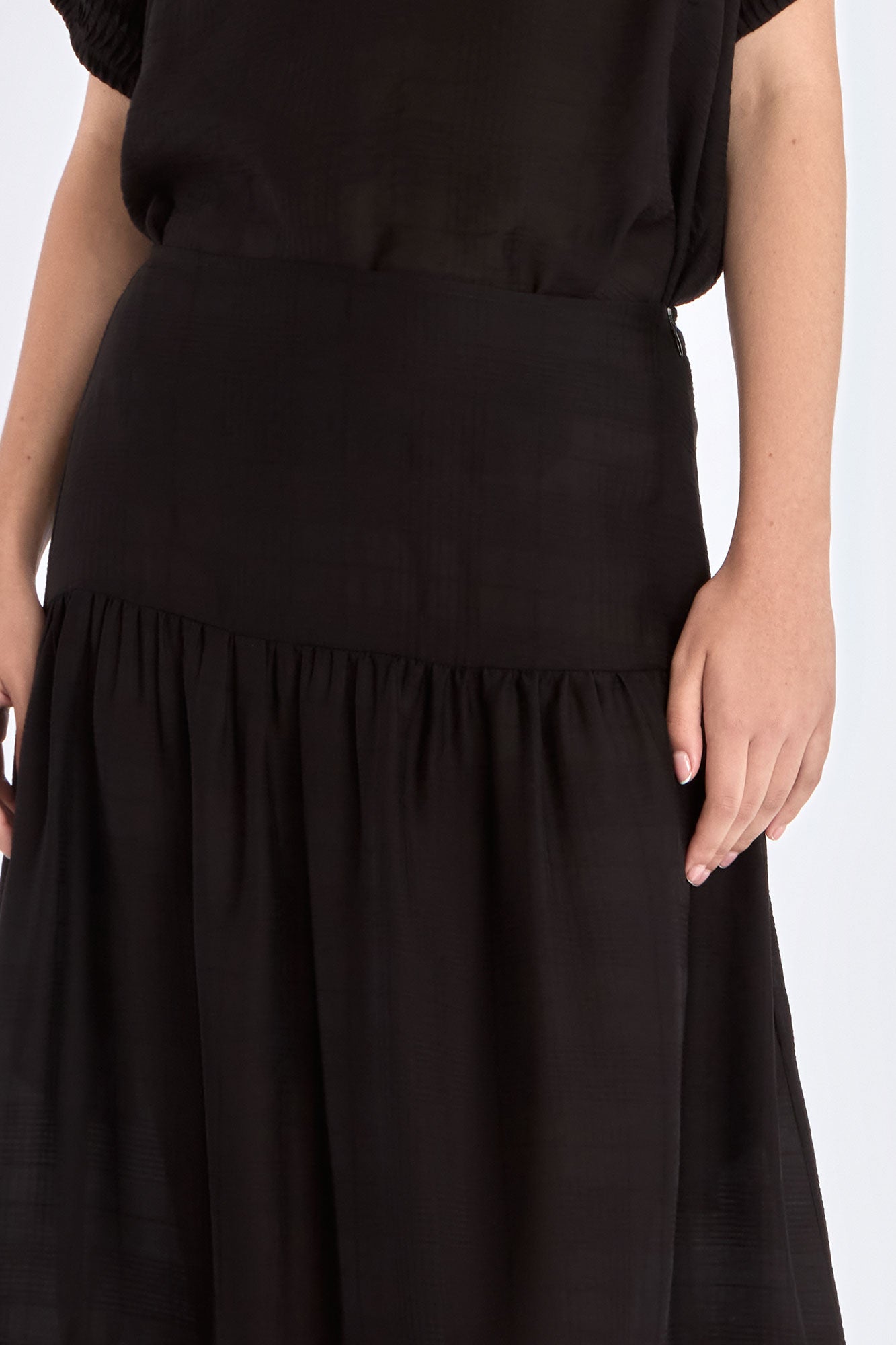 Subtle tonal trim and gathered fabric detail of the black Luanda Skirt.