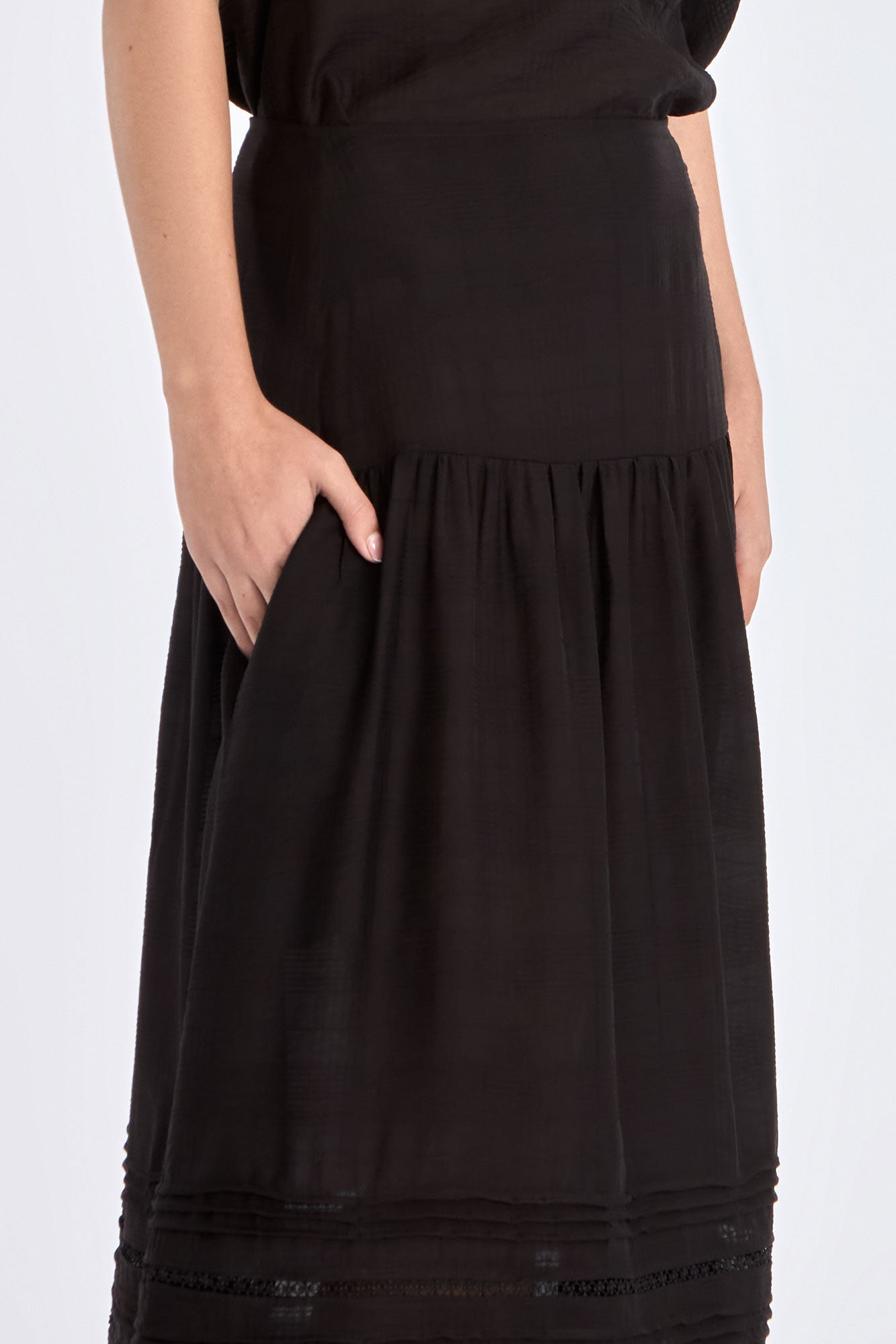Side view of the black Luanda Skirt, emphasizing the elegant movement of its gathered design.