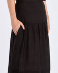 Side view of the black Luanda Skirt, emphasizing the elegant movement of its gathered design.