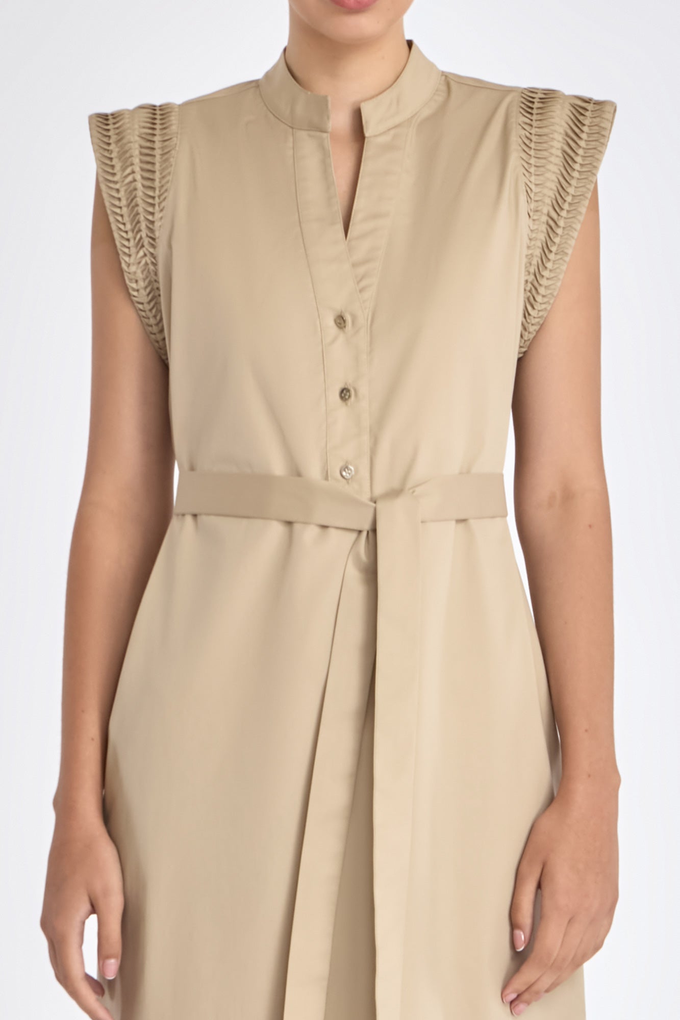 Detail shot of the V-neckline, metal button, and stretch cotton fabric of the Ecru Maki Dress.