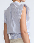 Oriana Blouse in Light Blue Stripes – Cotton blouse with V-neck, Neru collar, ruffled sleeves, appliqué trim, and tie-front hem.