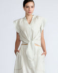 Oriana Blouse in Silver – Cotton blouse with V-neckline, Neru collar, ruffled sleeve details, tie hem, and appliqué embellishment.