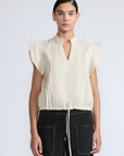 Pria Blouse in Prestine – Elegant sleeveless blouse in pima cotton with tonal V-neck, Greca trim, ruffle detail, and hem with pullers.