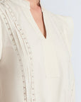 Pria Blouse in Prestine – Elegant sleeveless blouse in pima cotton with tonal V-neck, Greca trim, ruffle detail, and hem with pullers.